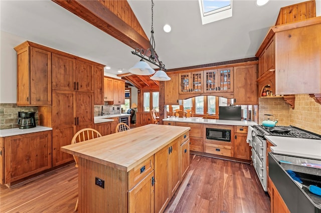 kitchen featuring tasteful backsplash, a kitchen island, decorative light fixtures, dark wood-type flooring, and black microwave