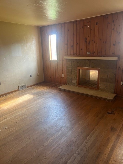 unfurnished living room with hardwood / wood-style floors and wooden walls