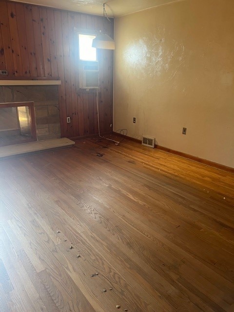 interior space featuring a stone fireplace, wood walls, and hardwood / wood-style floors