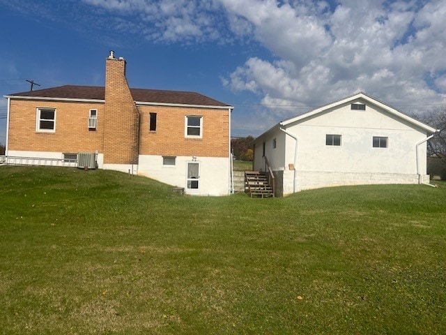 rear view of house with central AC and a yard