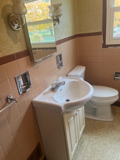 bathroom featuring toilet, vanity, and tile walls