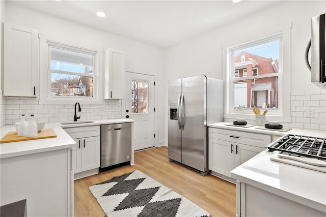 kitchen featuring sink, white cabinetry, plenty of natural light, stainless steel appliances, and light wood-type flooring