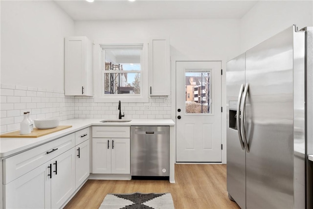 kitchen featuring sink, backsplash, stainless steel appliances, and white cabinets