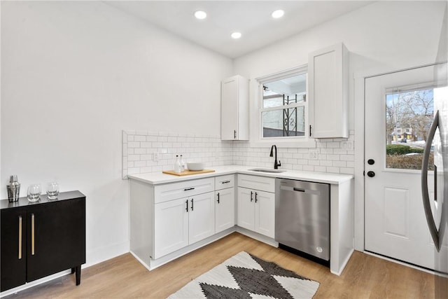 kitchen featuring stainless steel appliances, white cabinetry, sink, and light hardwood / wood-style flooring