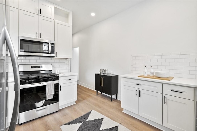 kitchen with tasteful backsplash, stainless steel appliances, light wood-type flooring, and white cabinets