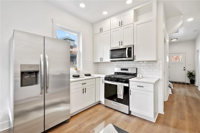 kitchen with white cabinetry, appliances with stainless steel finishes, light wood-type flooring, and decorative backsplash