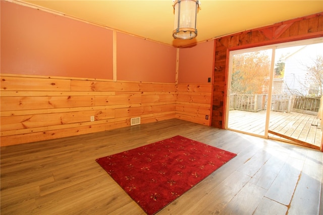 spare room featuring hardwood / wood-style flooring and wood walls