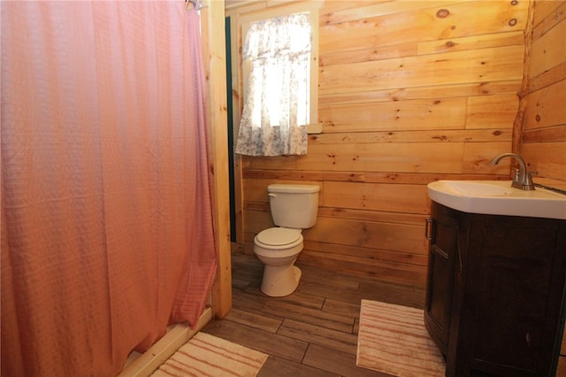 bathroom with toilet, wood-type flooring, curtained shower, vanity, and wood walls