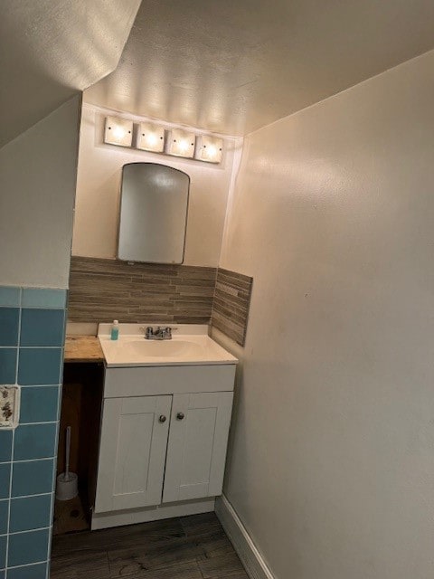 bathroom with vanity, hardwood / wood-style floors, tile walls, and vaulted ceiling