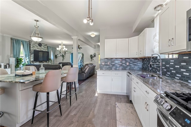 kitchen featuring stainless steel appliances, light stone countertops, a kitchen bar, light wood-type flooring, and white cabinets