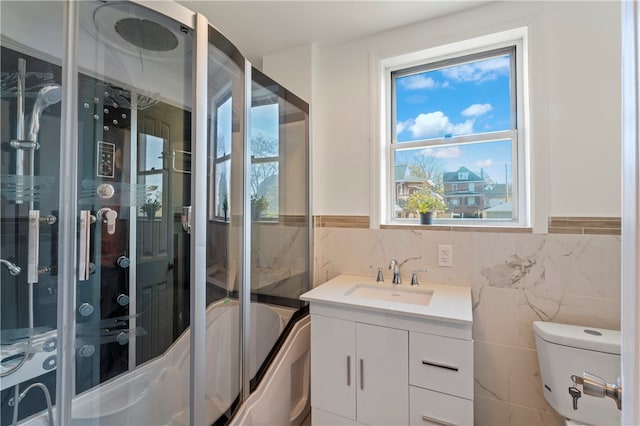 full bathroom with tile walls, vanity, bath / shower combo with glass door, and toilet