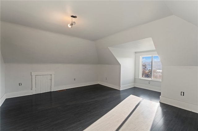 additional living space with dark wood-type flooring and vaulted ceiling