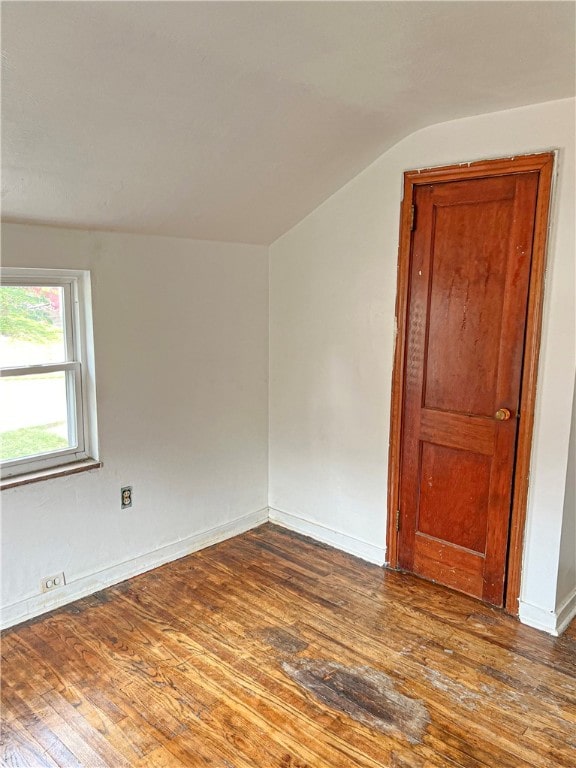 empty room featuring vaulted ceiling and dark hardwood / wood-style flooring