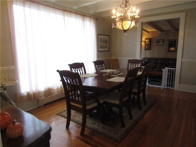 dining space with wood-type flooring, beam ceiling, and a chandelier