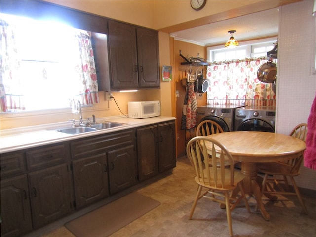 kitchen featuring independent washer and dryer, sink, dark brown cabinets, and crown molding