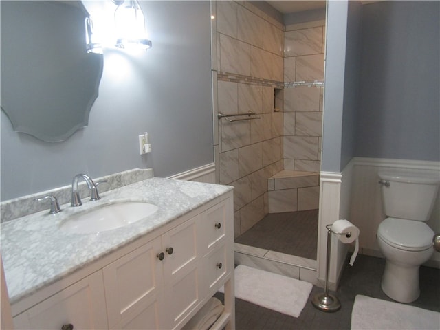 bathroom with toilet, vanity, tile patterned floors, and tiled shower