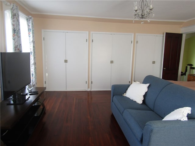 living room featuring dark wood-type flooring, a chandelier, and ornamental molding