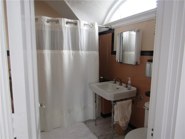 bathroom featuring a shower with shower curtain, toilet, and tile walls