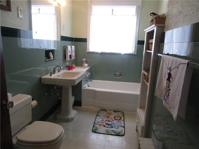 bathroom featuring a wealth of natural light, toilet, tile walls, and a tub