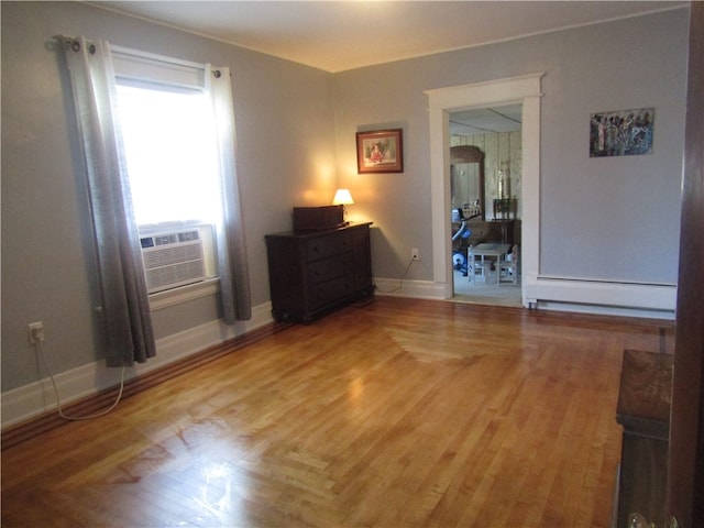 spare room featuring hardwood / wood-style flooring, cooling unit, and a baseboard heating unit