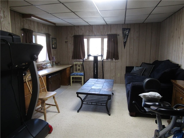 living room featuring a drop ceiling and wood walls