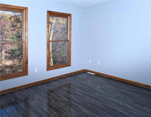 empty room with a healthy amount of sunlight and dark hardwood / wood-style flooring