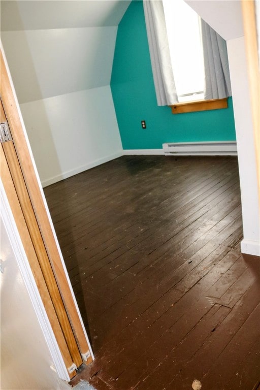 additional living space featuring dark wood-type flooring, vaulted ceiling, and baseboard heating