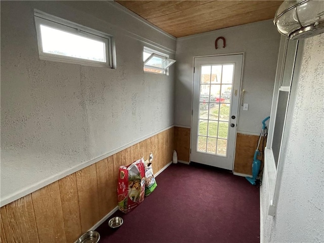 doorway featuring dark carpet, wooden ceiling, and wooden walls