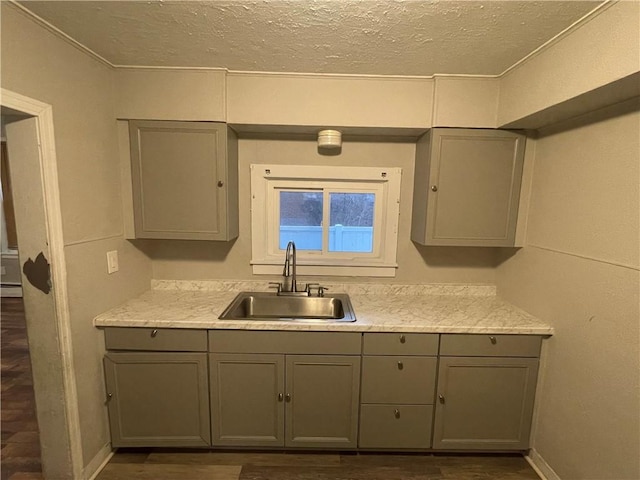 kitchen with a baseboard heating unit, sink, gray cabinets, light stone countertops, and a textured ceiling