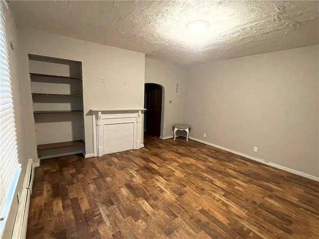 unfurnished bedroom featuring a textured ceiling, dark hardwood / wood-style floors, and a baseboard heating unit