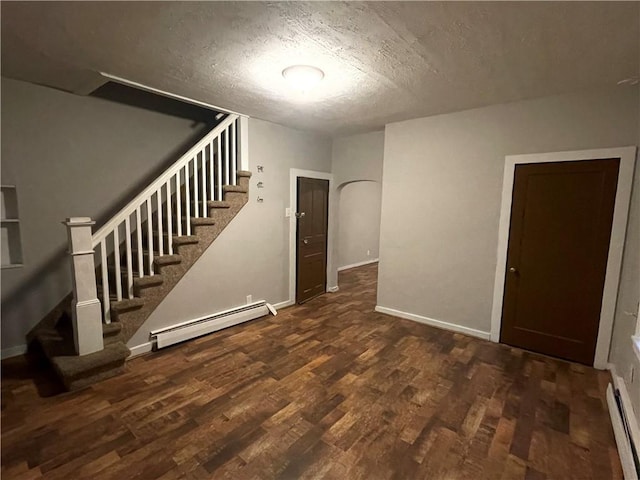 interior space with a textured ceiling, baseboard heating, and dark wood-type flooring