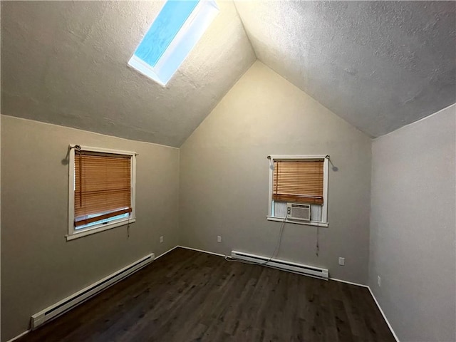 additional living space featuring hardwood / wood-style floors, lofted ceiling with skylight, baseboard heating, and a textured ceiling