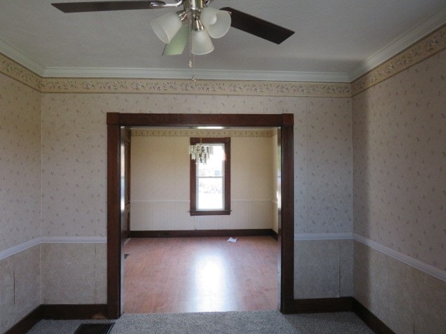 spare room featuring ornamental molding, hardwood / wood-style floors, and ceiling fan with notable chandelier