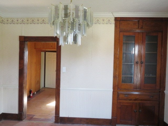 spare room with ornamental molding, hardwood / wood-style floors, and a chandelier