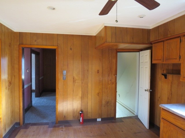 interior space featuring wooden walls, ceiling fan, and light hardwood / wood-style flooring