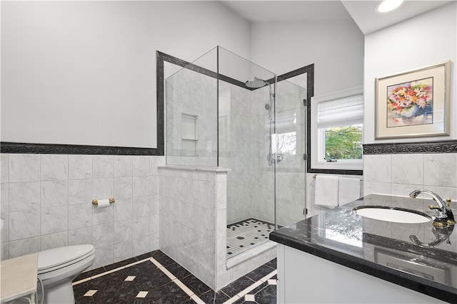 bathroom featuring toilet, vanity, a tile shower, and tile walls