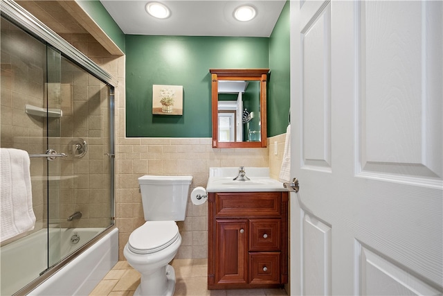 full bathroom featuring tile patterned flooring, combined bath / shower with glass door, vanity, toilet, and tile walls