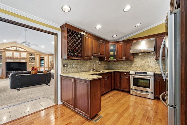 kitchen with appliances with stainless steel finishes, lofted ceiling, light hardwood / wood-style floors, and wall chimney range hood