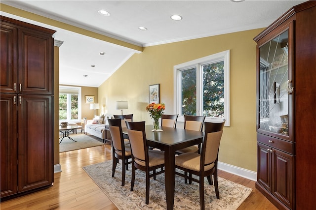 dining room featuring crown molding, light hardwood / wood-style flooring, and vaulted ceiling with beams