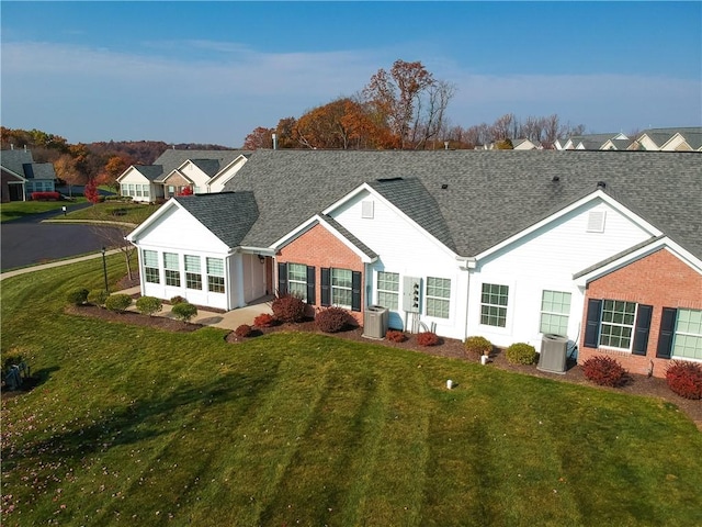 single story home featuring a sunroom, a front yard, and central AC