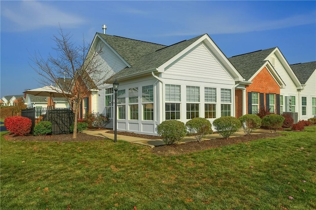 back of property with a sunroom and a yard