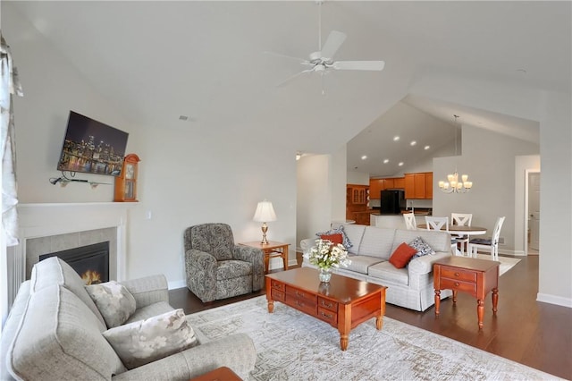 living room featuring a tile fireplace, ceiling fan with notable chandelier, wood-type flooring, and vaulted ceiling