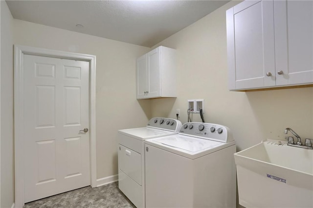 laundry room featuring washer and clothes dryer, cabinets, sink, and a textured ceiling