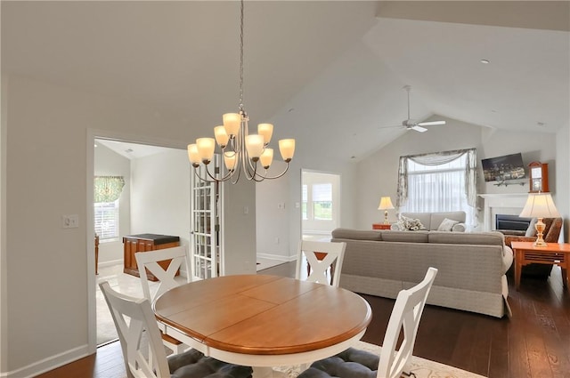 dining space with ceiling fan with notable chandelier, dark hardwood / wood-style floors, and vaulted ceiling