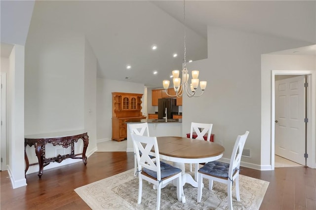 dining area featuring a chandelier, light hardwood / wood-style floors, and lofted ceiling