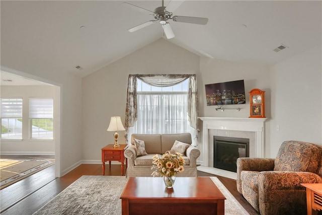 living room featuring a tile fireplace, a healthy amount of sunlight, vaulted ceiling, and wood-type flooring