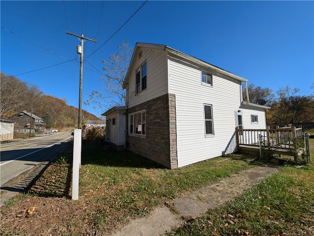 view of side of property with a wooden deck and a yard