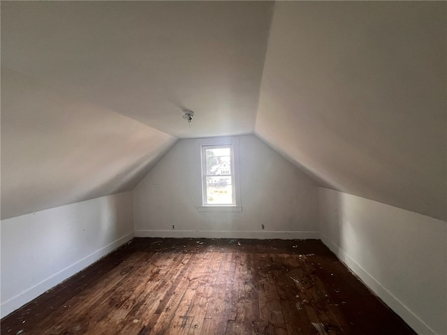 additional living space featuring dark wood-type flooring and lofted ceiling