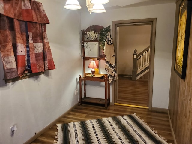 stairs featuring wood-type flooring and an inviting chandelier