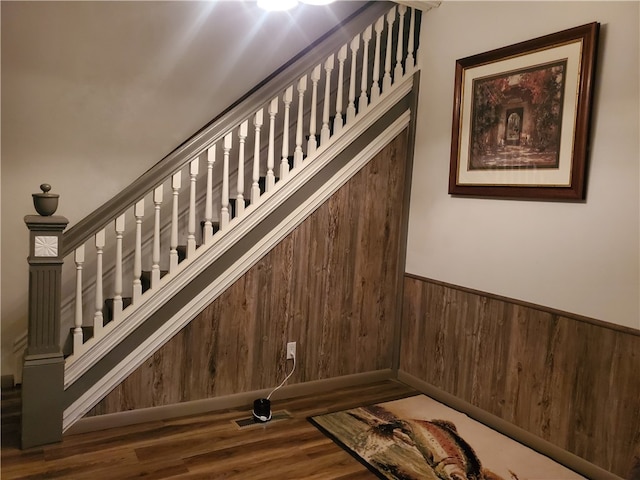 stairway with wood walls and hardwood / wood-style flooring